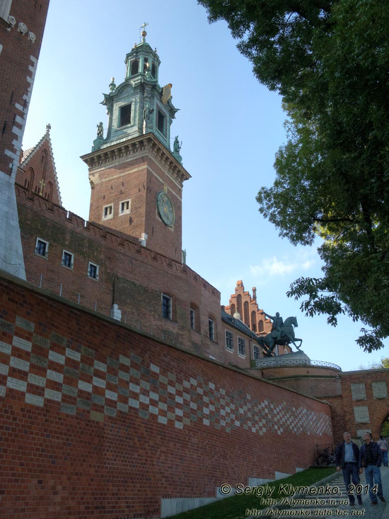 Фото Кракова. Вавель (Wawel). Стена с кирпичами с именами дарителей и Часовая башня (Wieza Zegarowa), вид со стороны подъезда к Гербовым воротам.